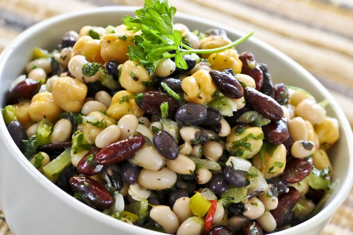 A colorful beans salad with butter beans, kidney beans, and black beans garnished with fresh parsley.