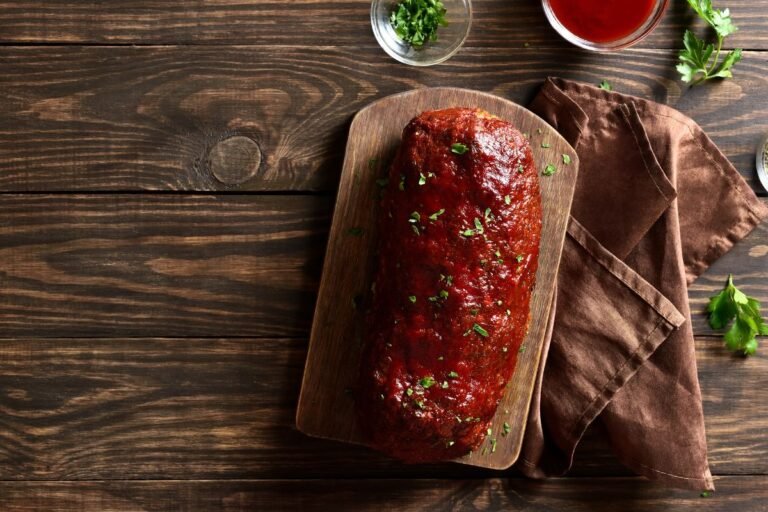 Savory meatloaf garnished with parsley on a wooden cutting board, ready to serve.