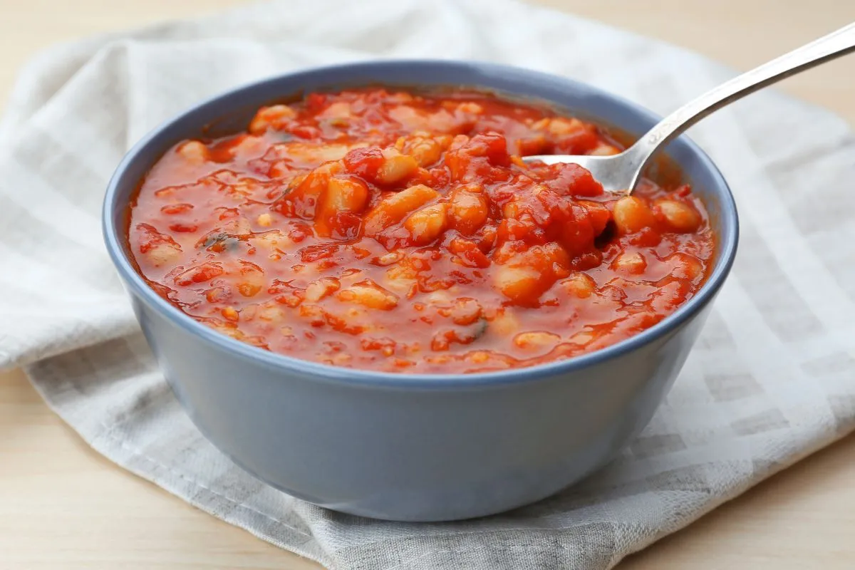 Bowl of homemade tomato-based butter bean soup on a wooden table