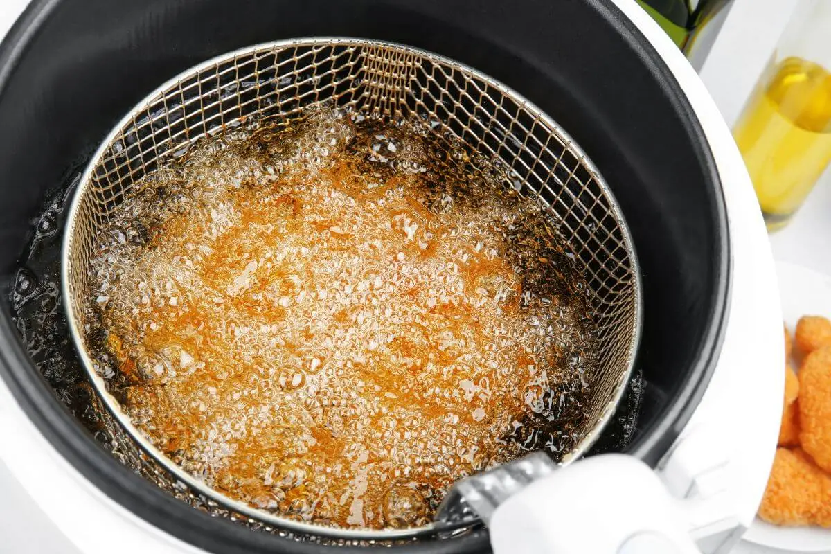 Boiling oil in deep fryer with metal basket for cooking