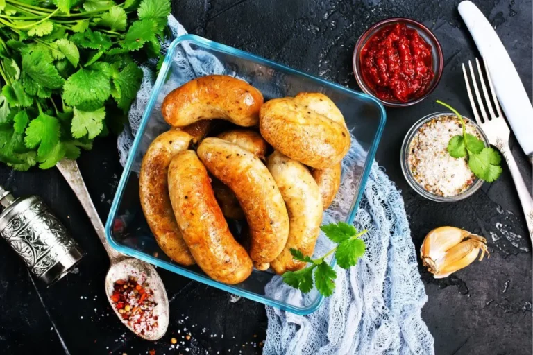 Juicy air-fried chicken sausages in a glass container, garnished with fresh cilantro, ready to serve.