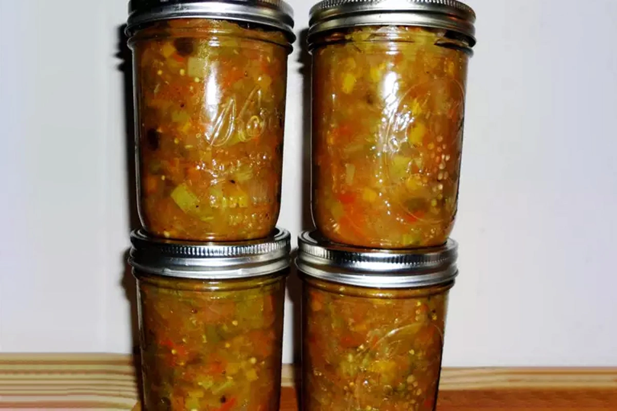 Jars of homemade chow chow relish on a wooden shelf