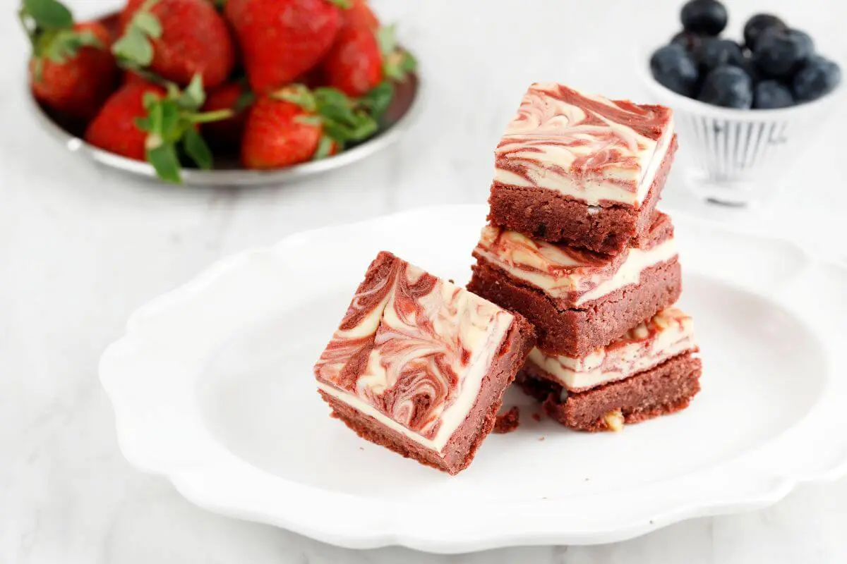 Red velvet brownies with cream cheese on white plate