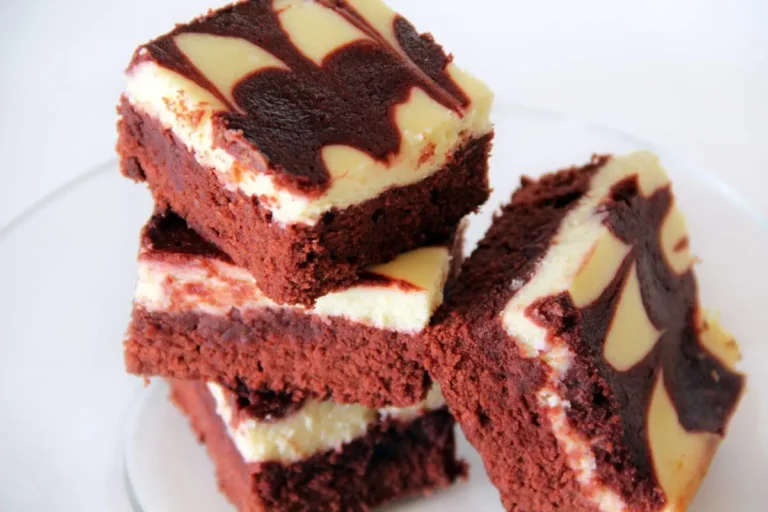 Red velvet cheesecake brownies stacked on a plate