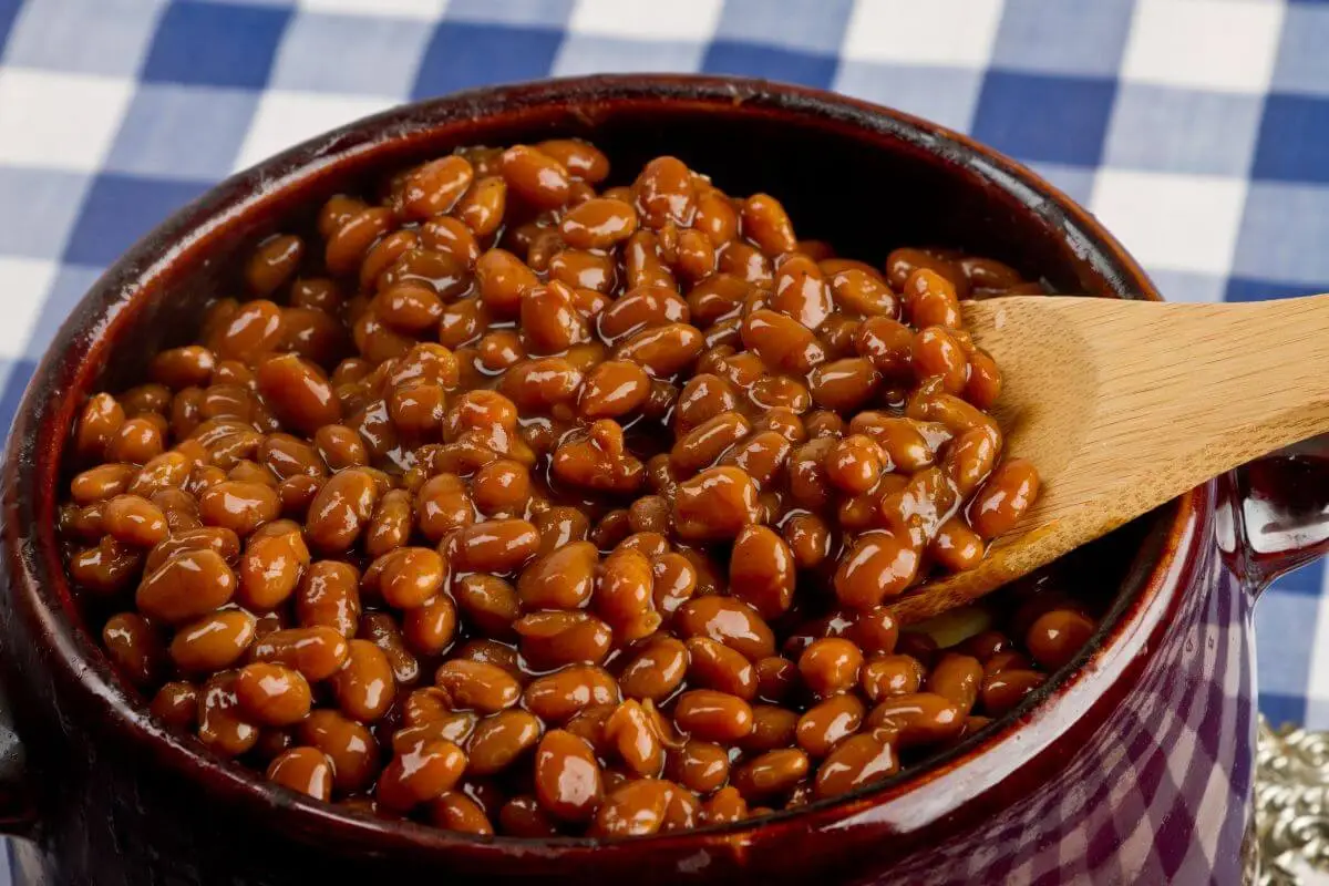 Pot of homemade baked beans with a wooden spoon