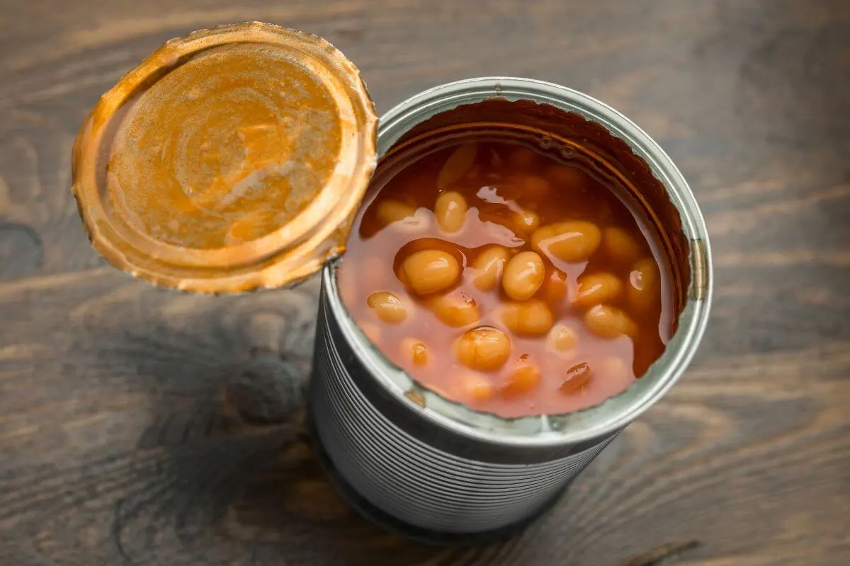 Opened can of baked beans on a wooden table