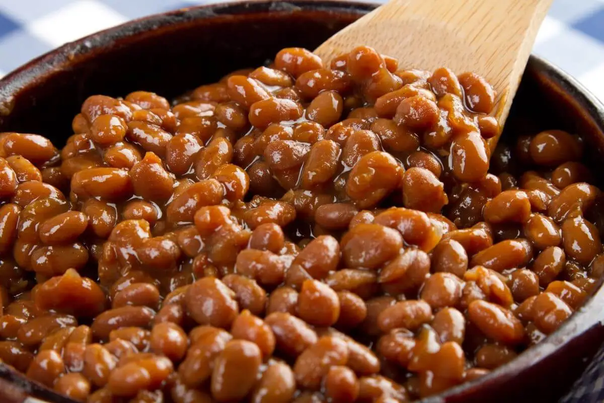 Close-up of baked beans with a wooden spoon