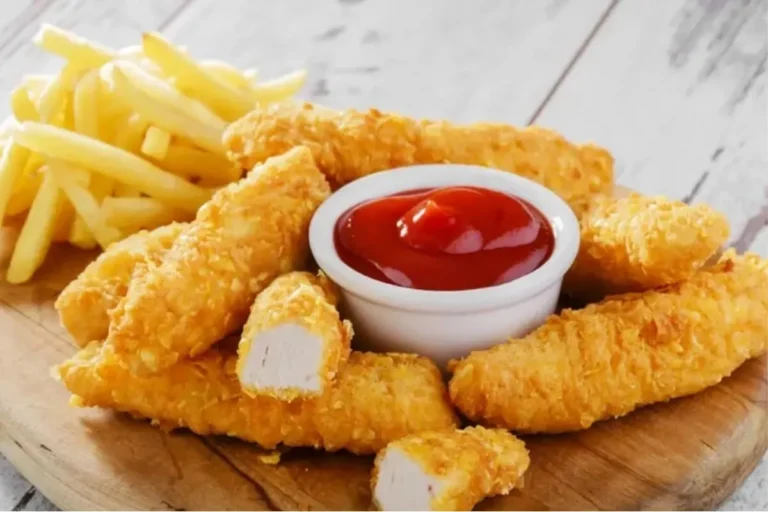 Golden crispy chicken fries on a plate with French Fries and Ketchup.