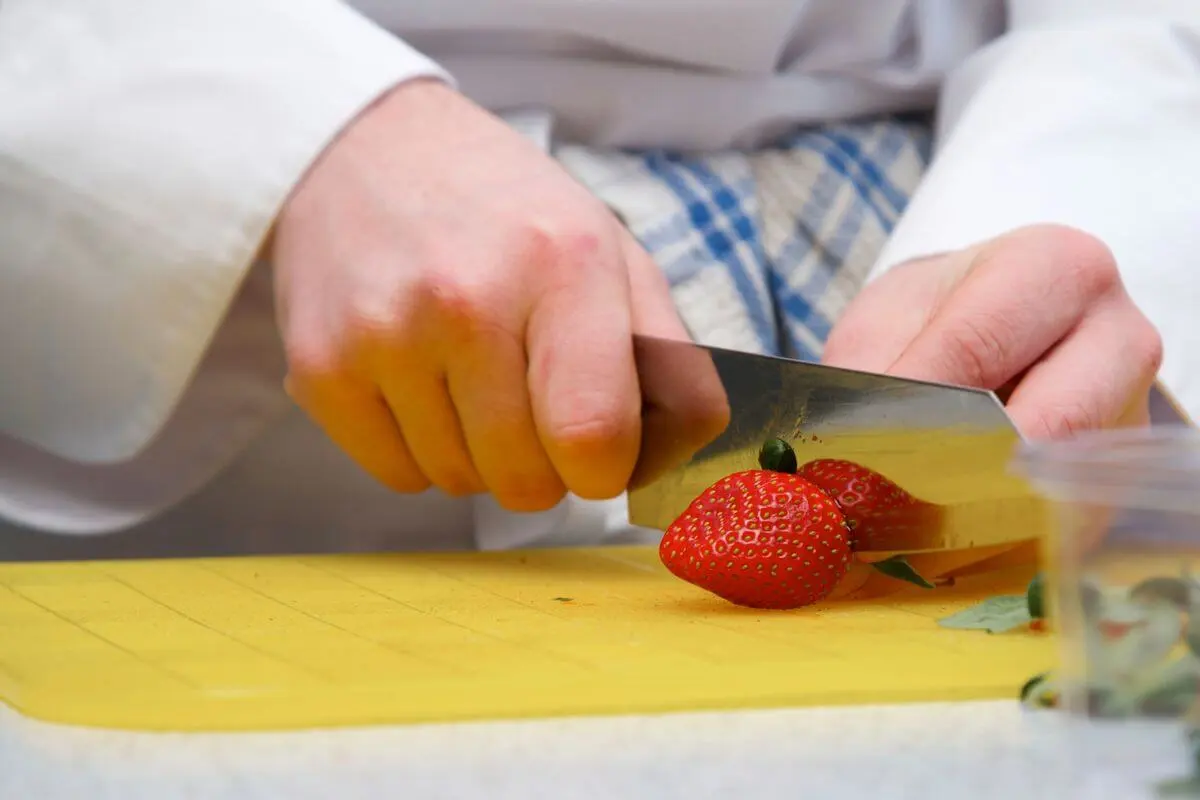 slicing strawberries on a yellow cutting board