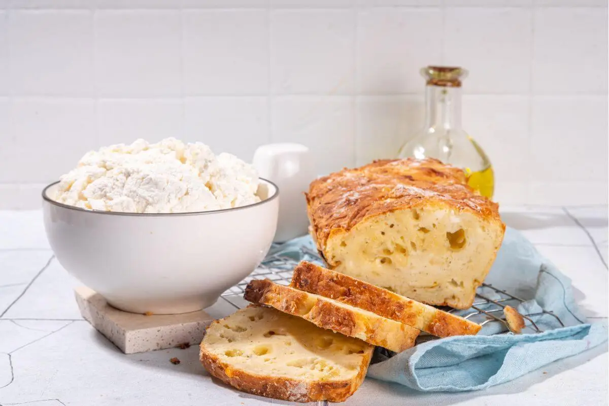 Cottage cheese bread made with two ingredients, sliced and arranged with a bowl of cottage cheese.