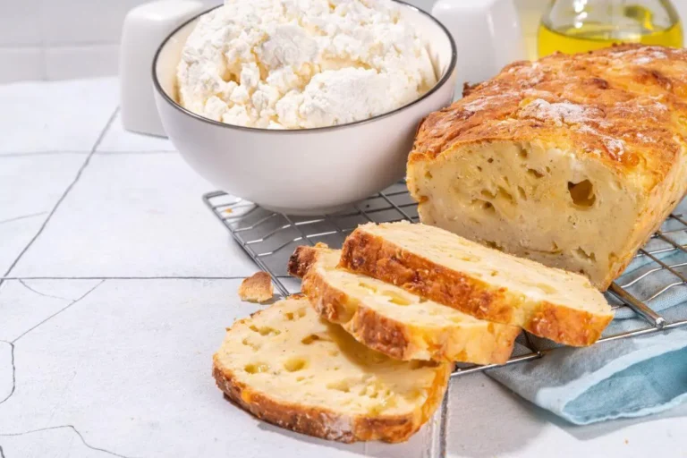 Freshly baked cottage cheese bread with a bowl of cottage cheese and olive oil on a kitchen counter.