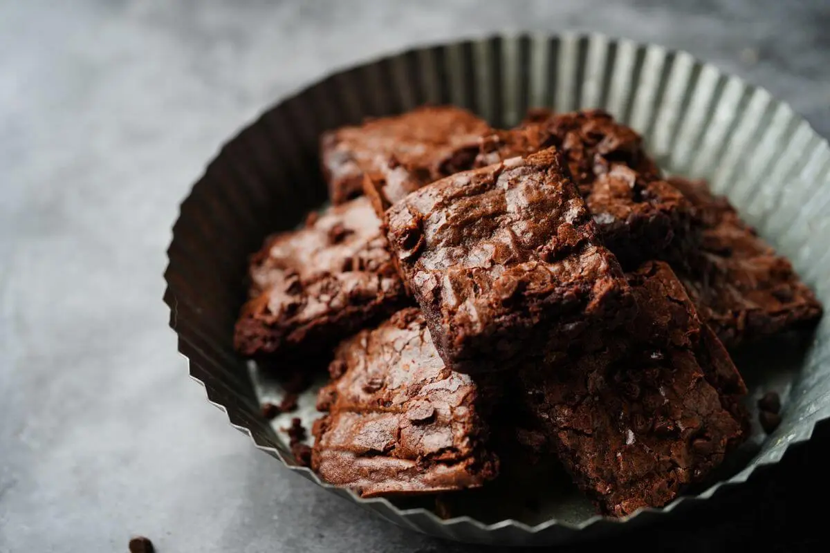 Chocolate brownies with rich, crinkly crust in a rustic setting.