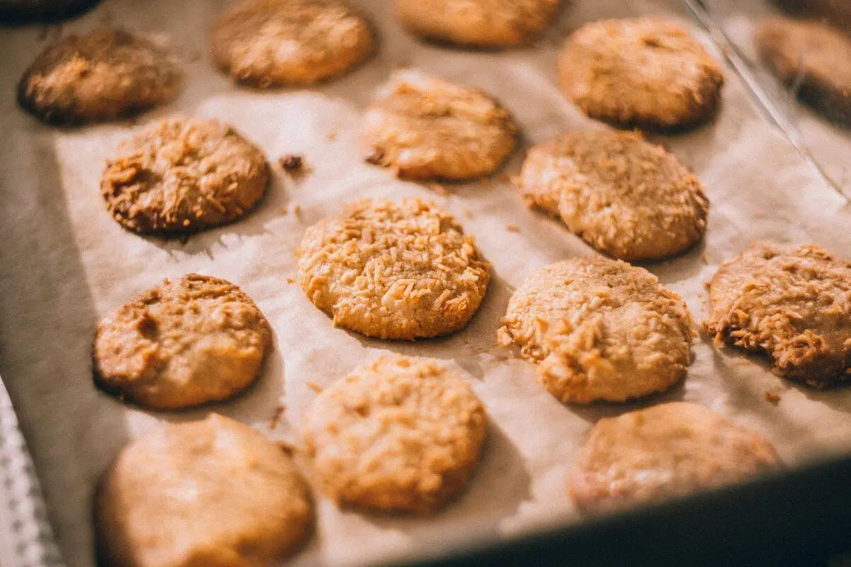 Freshly baked golden cookies sprinkled with flakes on parchment.